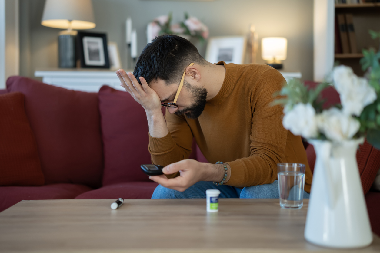 Stressed man checking blood sugar with glucose meter
